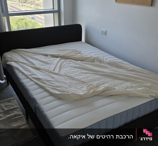 חדר עם מיטה ליד חלון ונוף עירוני